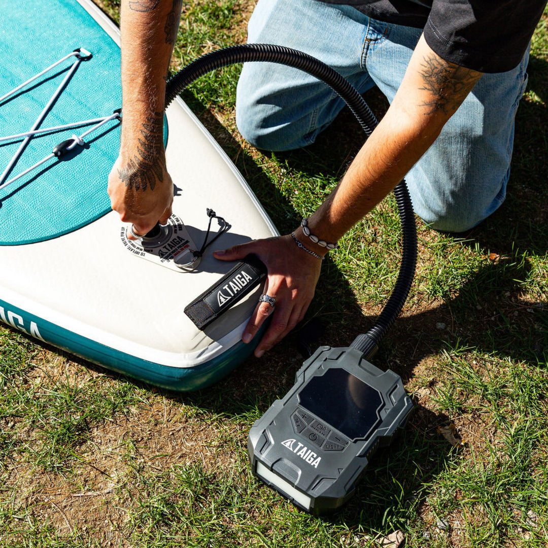 Person inflating a stand-up paddleboard with a battery pump