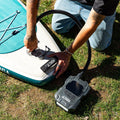 Person inflating a stand-up paddleboard with a battery pump