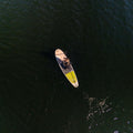Person paddleboarding on dark blue water from an aerial perspective