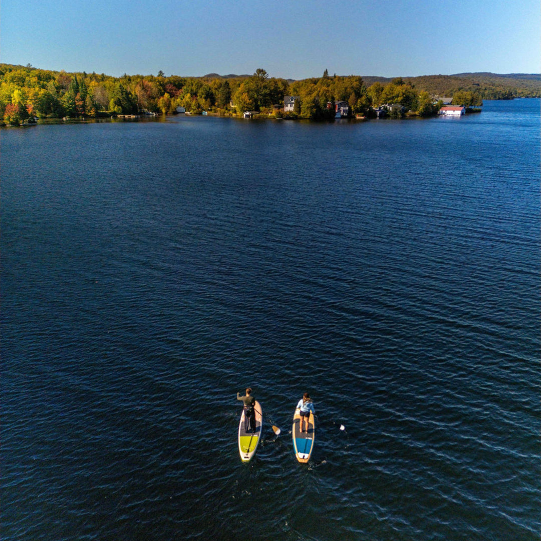 Two paddle boarders on a calm lake with a scenic background