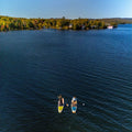 Two paddle boarders on a calm lake with a scenic background