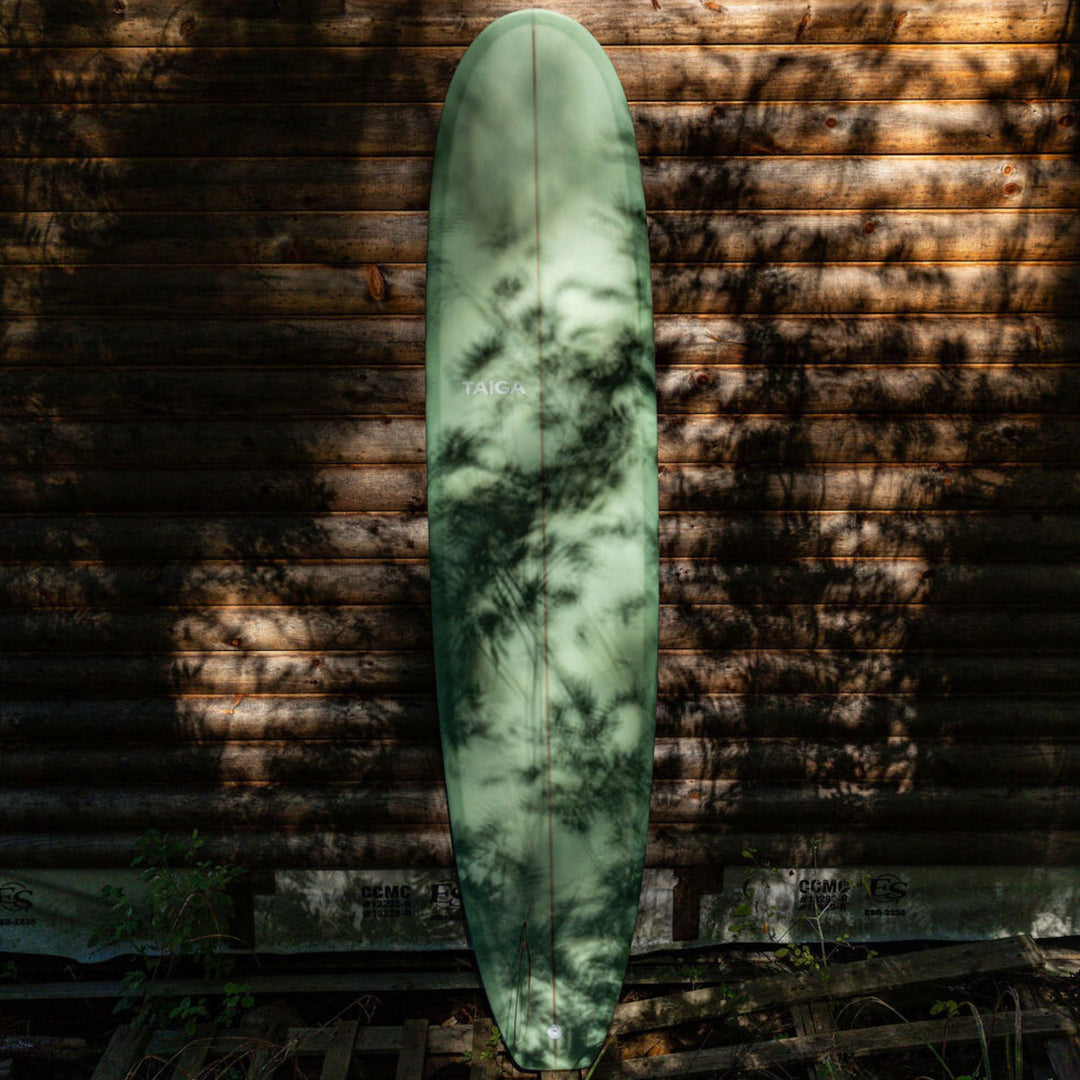 Green surfboard leaning against a wooden wall