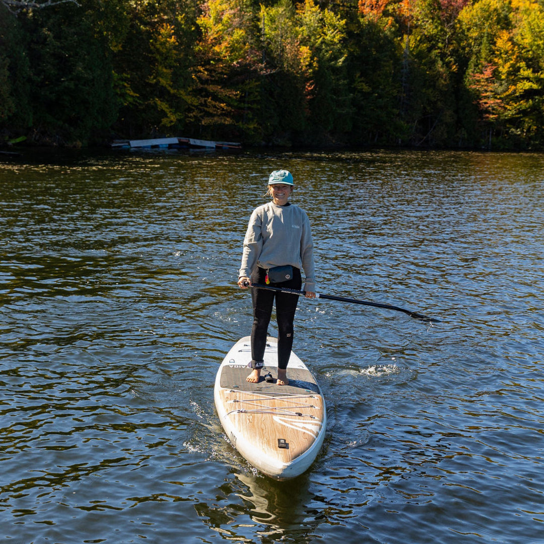 Person standing on a paddleboard, wearing a crewneck with 'Slow Rider Club' text.