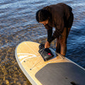 Person preparing a paddleboard by the water