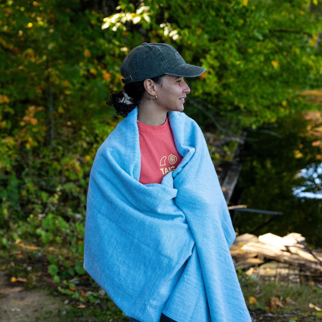 Person wrapped in a surf sock bag with a Taiga tee and a baseball cap
