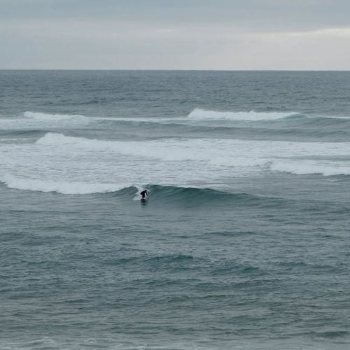Person surfing a wave in the ocean on a cloudy day