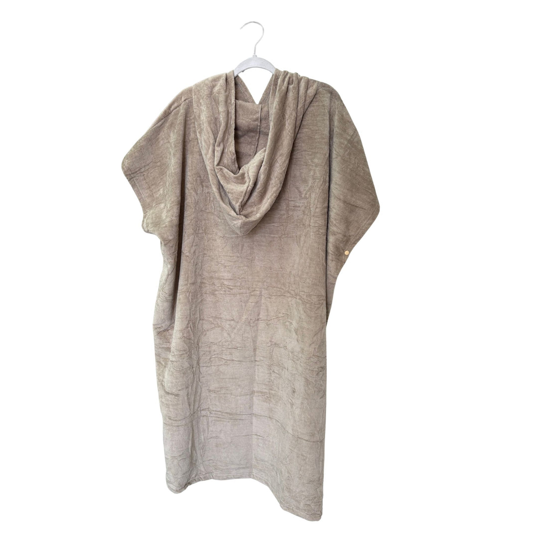 Beige poncho on a white hanger against a white background