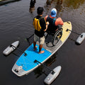 Two people on an Adaptive Inflatable Paddle Board with stabilizers in calm water.