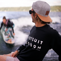 Surfer wearing the black WETSUIT SEASON Crewneck by TAIGA BOARD